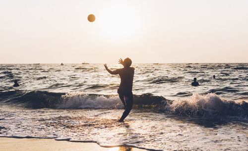 Man playing with ball in sea against sky