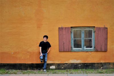 Teenage boy standing against house