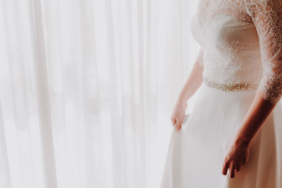 Midsection of bride wearing wedding dress