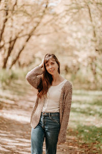 Portrait of a girl with brown hair, in a cardigan, on a walk in the forest.