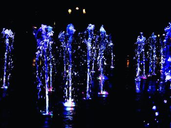 Silhouette illuminated lights against sky at night
