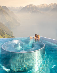 People swimming in pool against sea