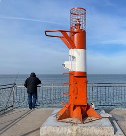 Rear view of man standing by sea against sky