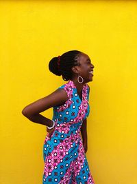 Cheerful woman standing against yellow background