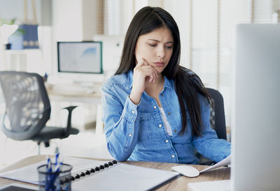 Young woman using mobile phone while sitting on table