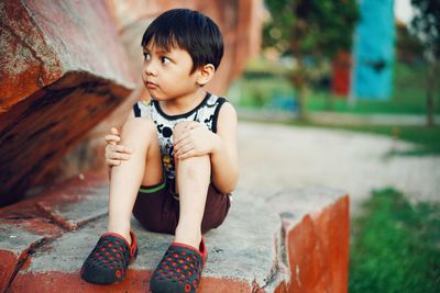 Cute boy looking away while sitting outdoors