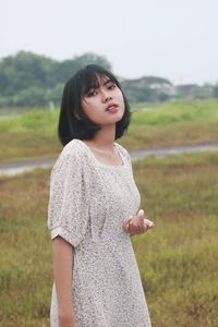 Portrait of young woman standing against sky