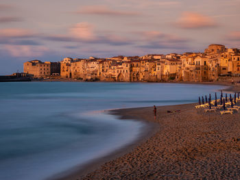 Scenic view of beach in city during sunset