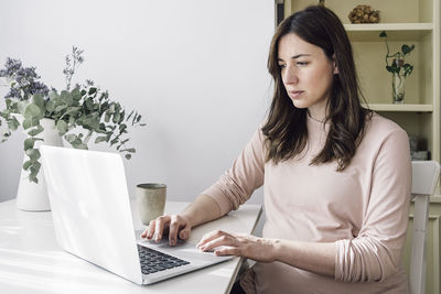 Young woman using phone while sitting on table