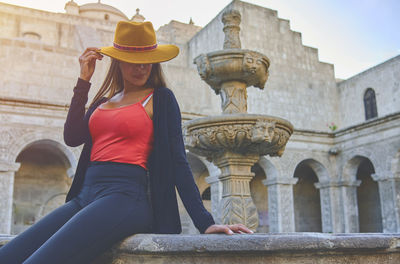 Side view of woman looking away while standing against historic building