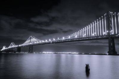 Illuminated suspension bridge over river at night