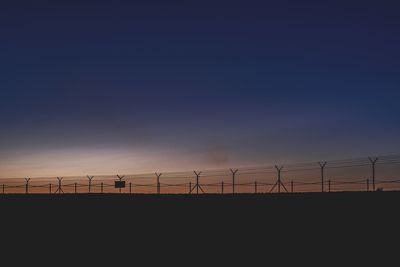 Silhouette of electricity pylon against sky during sunset