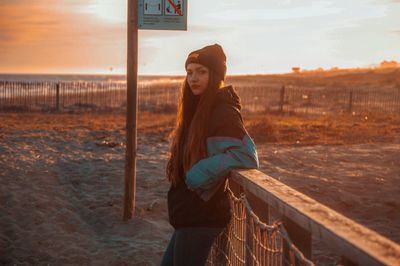 Portrait of smiling young woman standing against sky during sunset