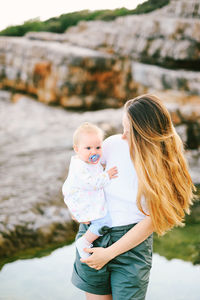 Mother carrying son while standing outdoors