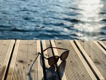 Black sunglasses on wooden pontoon near the water