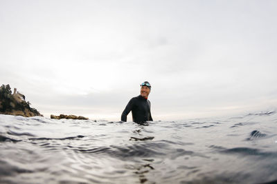 Male swimmer standing waist deep in sea water