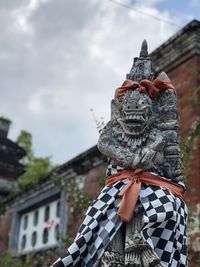 Low angle view of statue against building against sky