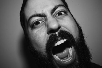 Close-up portrait of mid adult man screaming against wall