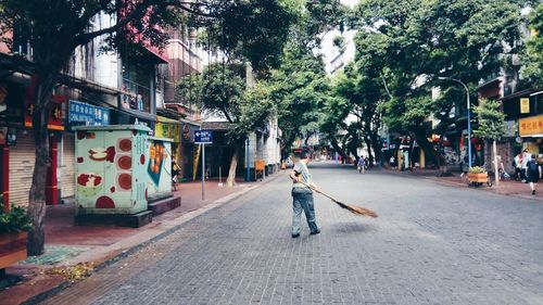 Man walking on road along trees