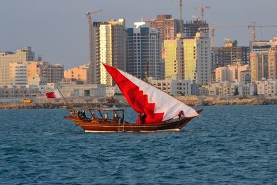 Boat sailing on sea against buildings in city