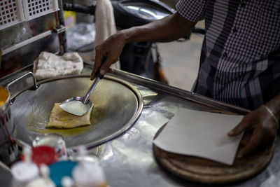 Thai man cooking and selling traditional thai sweet pancakes on the street