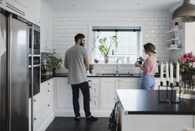 Rear view of mid adult couple working in kitchen at home