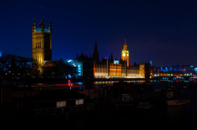 Illuminated buildings in city against clear sky at night