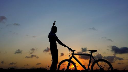 Silhouette man with bicycle against sky during sunset