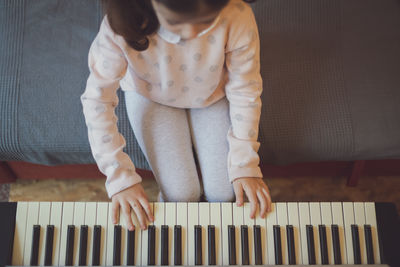 A little girl plays the electric piano.