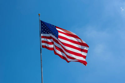 Low angle view of american flag against blue sky