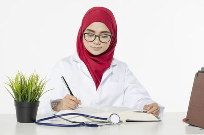 Portrait of woman holding eyeglasses on white table