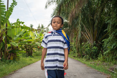 Portrait of boy with malaysian flag standing on road 