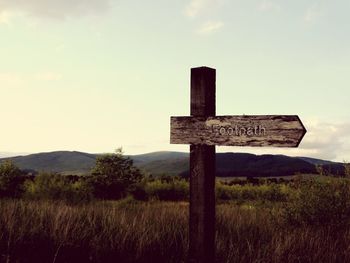 Information sign on field against sky