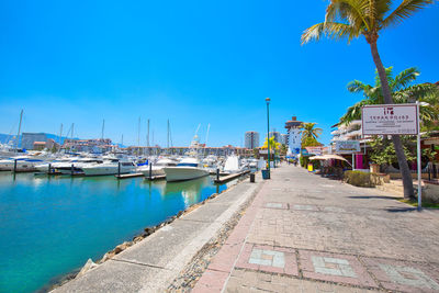 Sailboats moored at harbor against blue sky