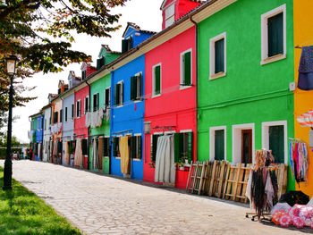 Rear view of people walking on street by multi colored buildings