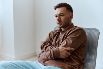 Young man sitting on bed at home