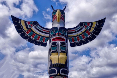 Low angle view of totem pole against cloudy sky