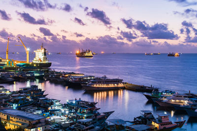 Boats moored at harbor against sky during sunset