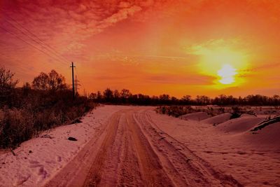 Road passing through field during sunset