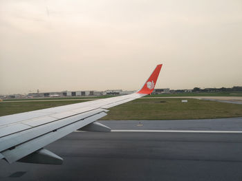 Airplane flying over airport runway against sky