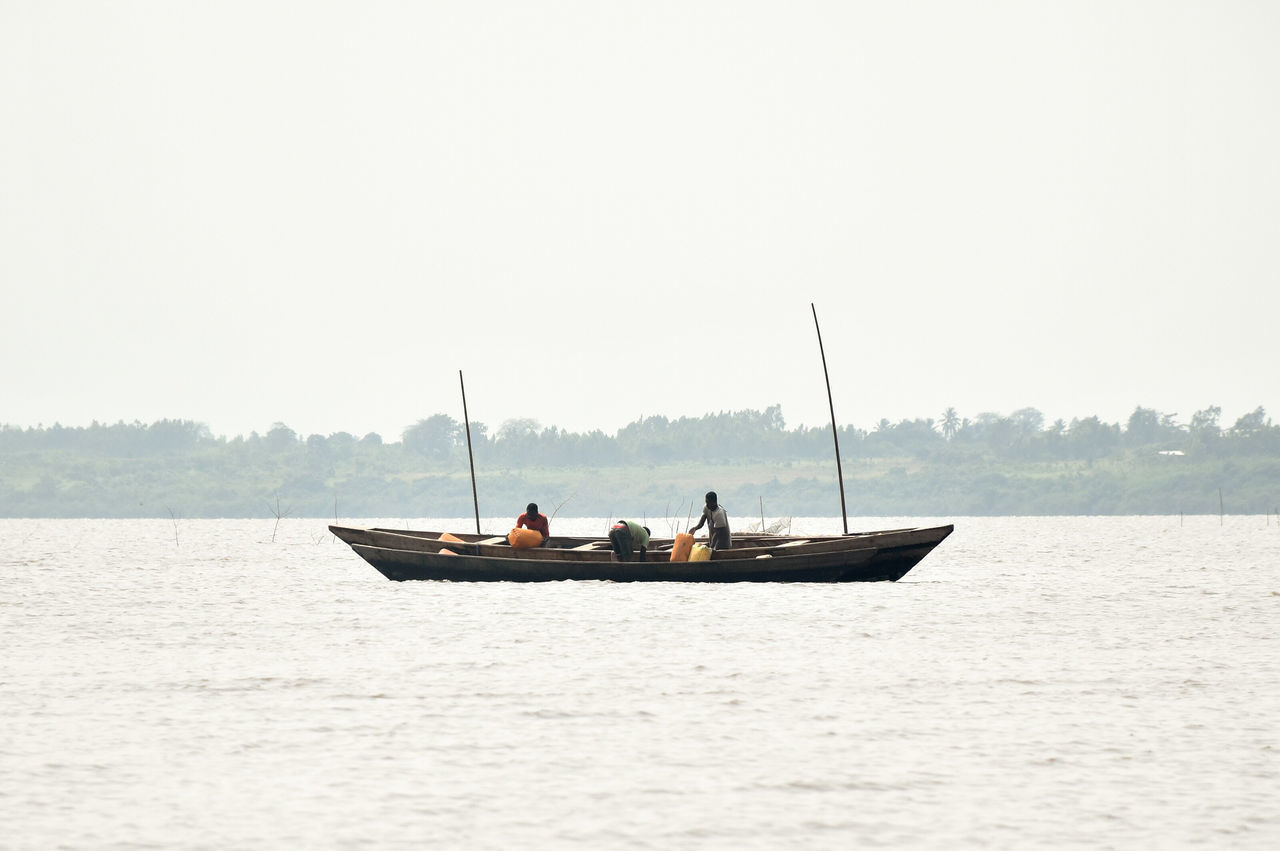 PEOPLE ON LAKE AGAINST CLEAR SKY