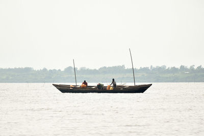 People on boat against clear sky