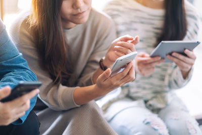 Midsection of friends using phone while siting in office