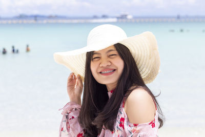 Portrait of beautiful woman wearing hat at beach