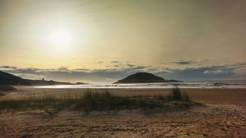 Scenic view of beach against sky at sunset