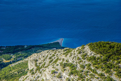 High angle view of sea and mountains against blue sky