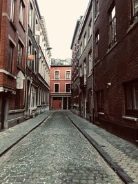 Footpath amidst buildings against sky