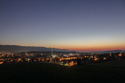 Illuminated cityscape against clear sky at night