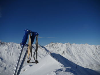 Ski pole on snowy mountain against clear blue sky