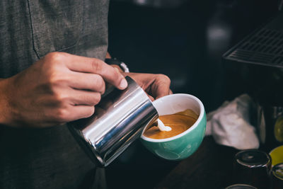 Midsection of man holding coffee cup on table